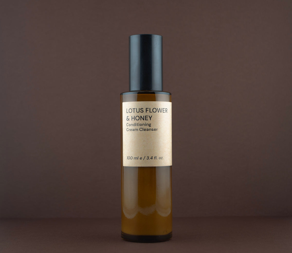 Front view of Lotus Flower & Honey Conditioning Cream Cleanser (100 ml / 3.4 fl. oz.) in an amber glass pump bottle.