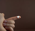 Texture shot of Palo Duro barrier repair cream showing a rich, white dollop of moisturizer on a fingertip.