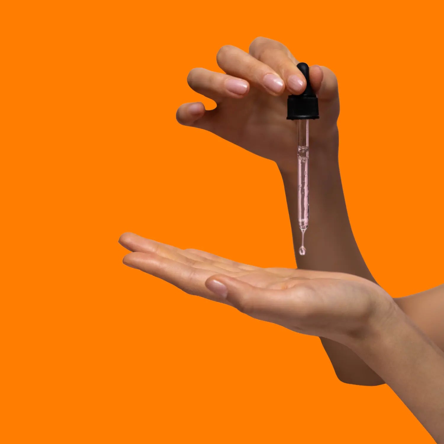Hand holding a dropper with clear liquid over another hand against an orange background