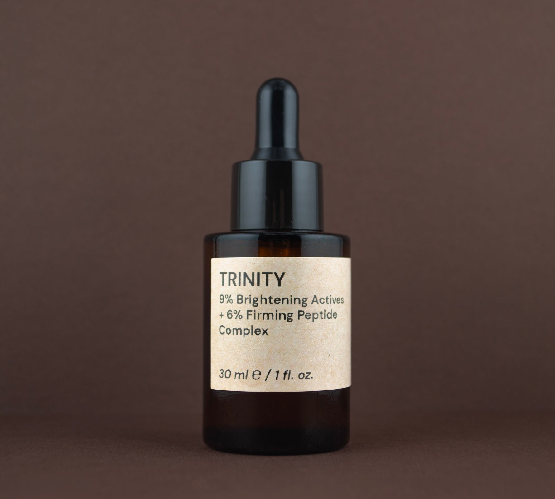 Front view of Trinity 9% Brightening Actives + 6% Firming Peptide Complex (30 ml / 1 fl. oz.) in an amber glass dropper bottle.