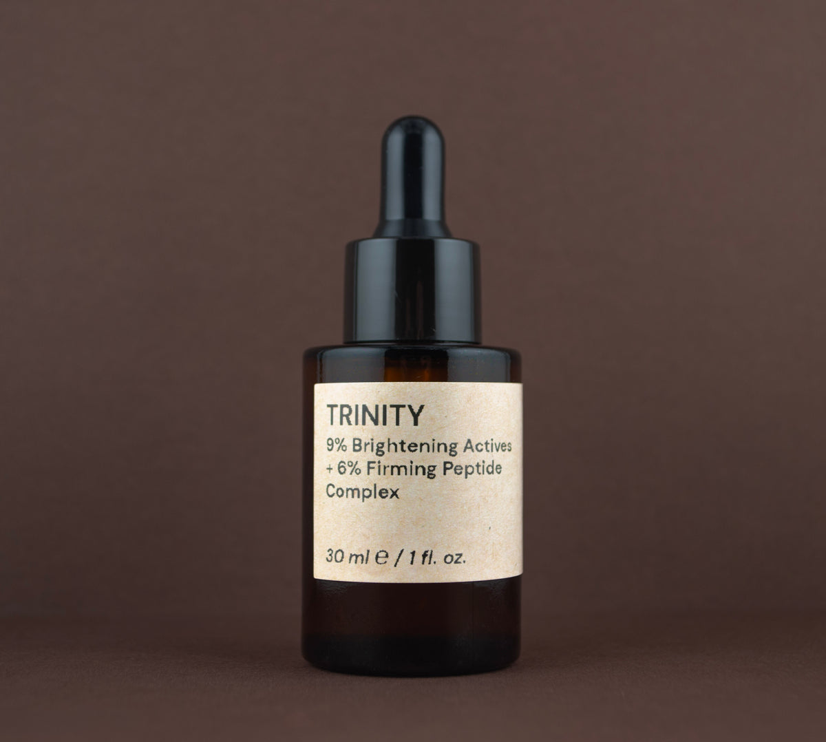 Front view of Trinity 9% Brightening Actives + 6% Firming Peptide Complex (30 ml / 1 fl. oz.) in an amber glass dropper bottle.