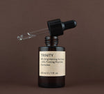 Open bottle of Trinity brightening and firming peptide complex showing the glass dropper pipette resting on the rim.